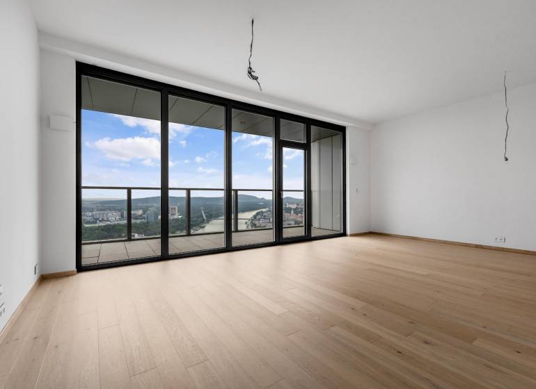 A spacious living area with large windows and wood-patterned flooring in a 3-room apartment.