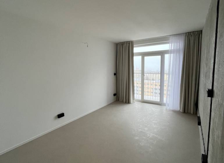 Studio apartment with large windows, light curtains, and light flooring with a view of the city.