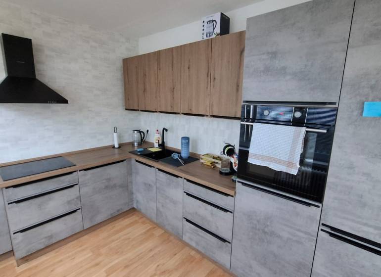 A kitchen in a 3-room apartment with a wooden decor floor and modern appliances.