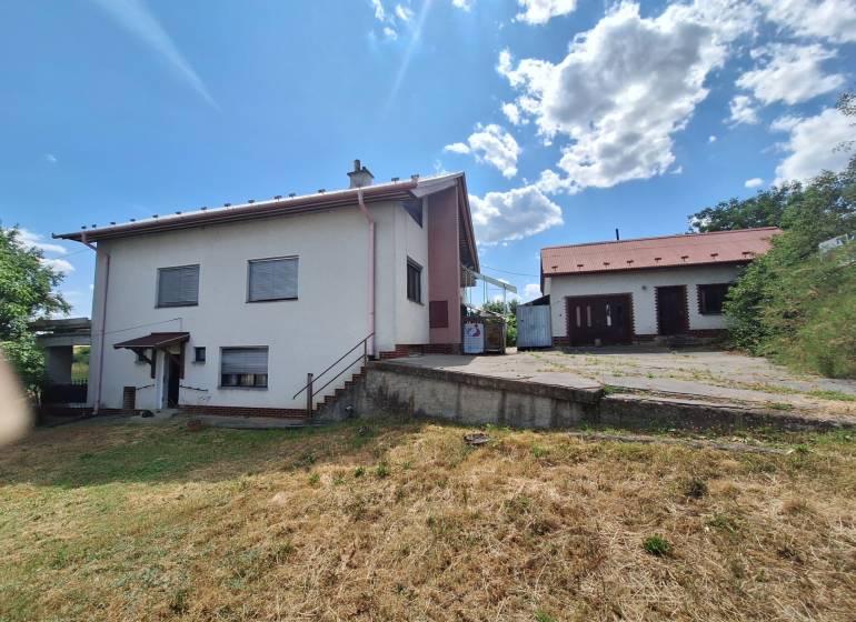 A family house in Nová Bašta with a grassy plot and an annex under the blue sky.