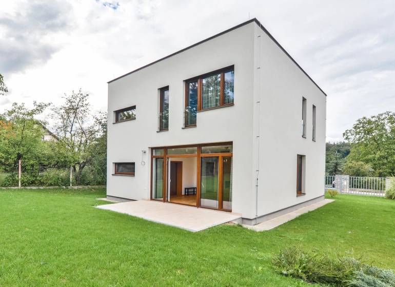 A family house in Žilina with a simple facade, lawn, and a terrace in the garden.
