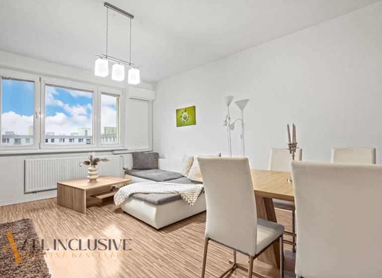 Living room in a three-room apartment with light-colored walls and a wooden decor floor.