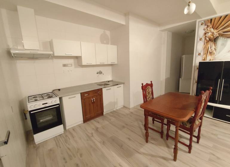 Kitchen in a 2-room apartment with a dining table, floor with wooden decor.