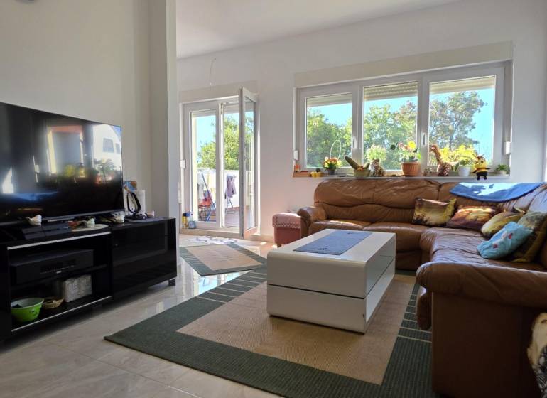 Living room with a brown leather sofa and decorative pillows in a three-room apartment.