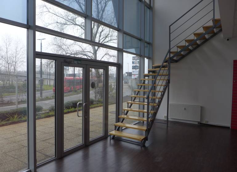 Interior of commercial spaces with wood-patterned flooring and a staircase.