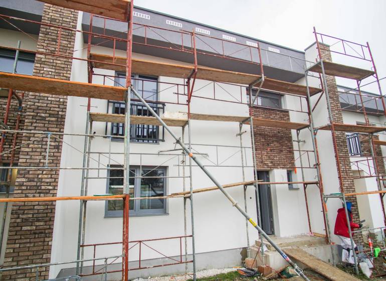 A family house in Nové Zámky during renovation with scaffolding and brick detail on the facade.