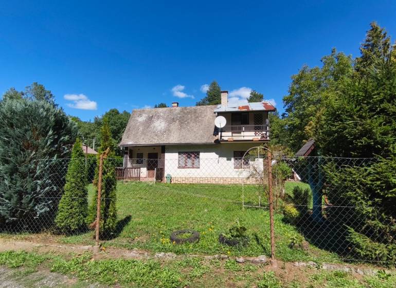 A cottage in Dolné Strháre with a garden, surrounded by greenery and a blue sky.