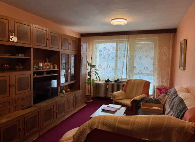 Living room in a 3-room apartment with rustic furnishings, carpets, and curtains.
