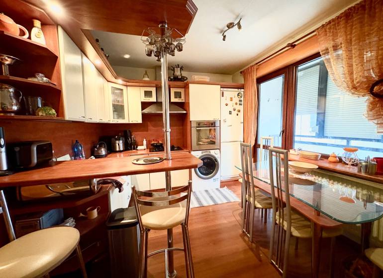 A kitchen in a 3-room apartment with a wooden decor floor and a glass dining table.