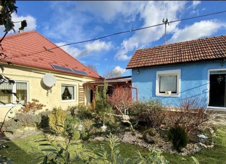 A family house in Tvrdomestice with two colorful houses, a garden, and a solar panel.