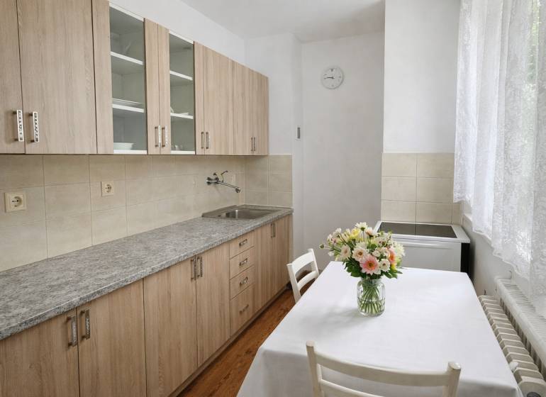 A kitchen in a studio apartment with a kitchen unit and a wooden decor floor.