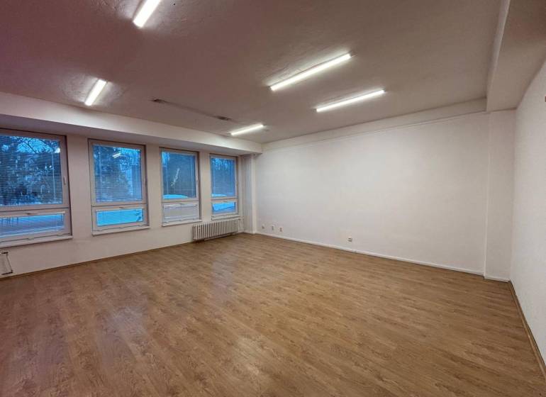 Offices with light walls and wooden decor flooring, large windows.