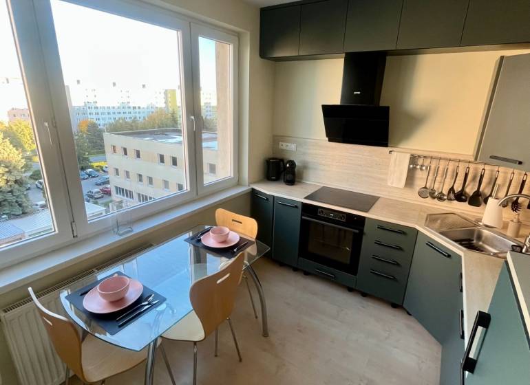 A kitchen in a 2-room apartment with a view, glass table, wooden floor decor.
