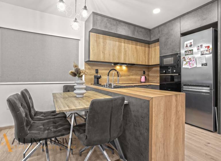 A kitchen corner with a wooden decor in a 3-room apartment with a stylish table and gray chairs.