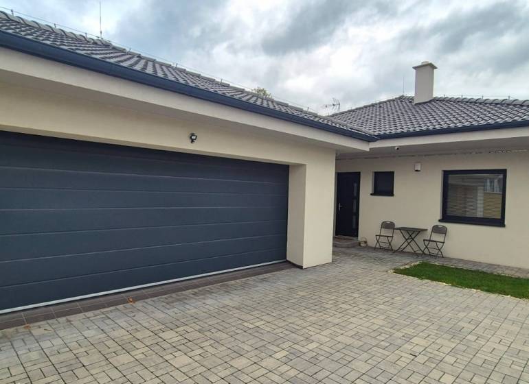 A family house in Studienka with two chairs and a table on a paved courtyard.