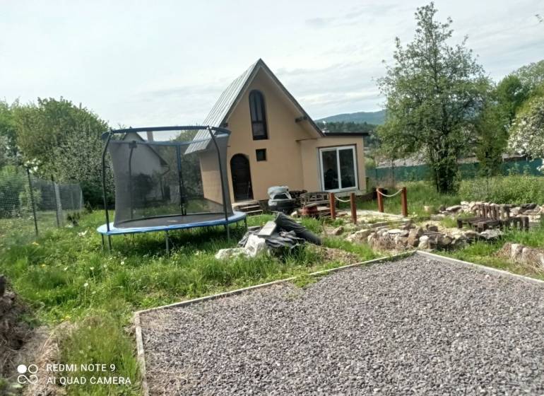 Cottage in Hliník nad Hronom with a trampoline and a gravel path in the garden.