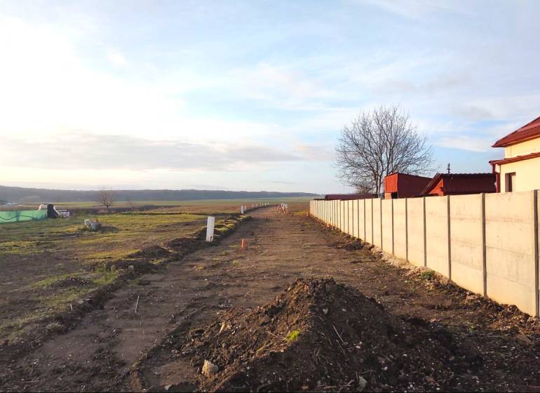 A residential plot in Cabaj-Čápor, bordered by a fence and a tree in the background.