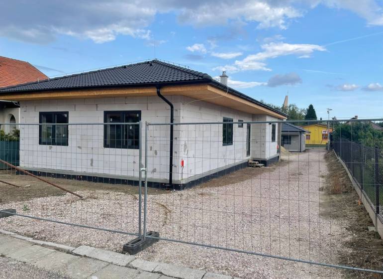 A family house with a sloped roof and white facade is being constructed in Radava.