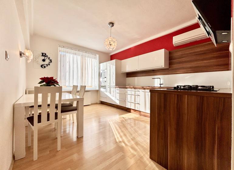 A kitchen in a 2-room apartment with a wooden decor floor and a dining table.