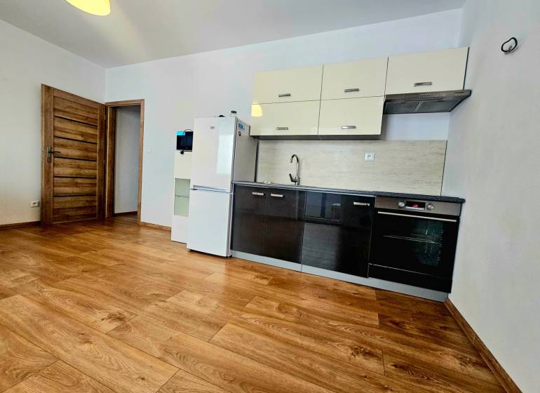 A kitchen in a 2-room apartment with a wooden decor floor and furnishings.