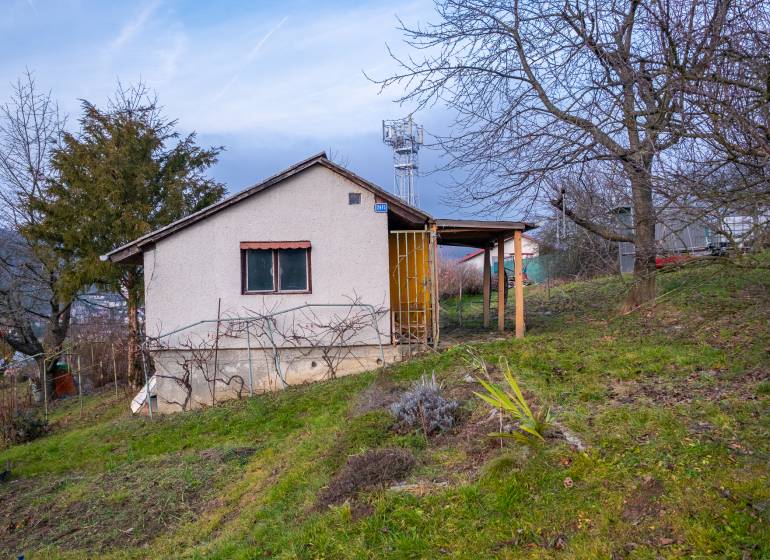 A cottage in Prešov surrounded by fruit trees and lush greenery on a sloping plot.