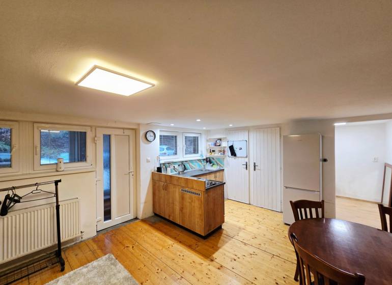 A kitchen in a studio apartment with a wooden decor floor and a table.