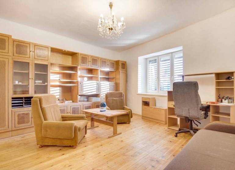 Interior of a family house with furniture, wood-patterned flooring, and a chandelier.