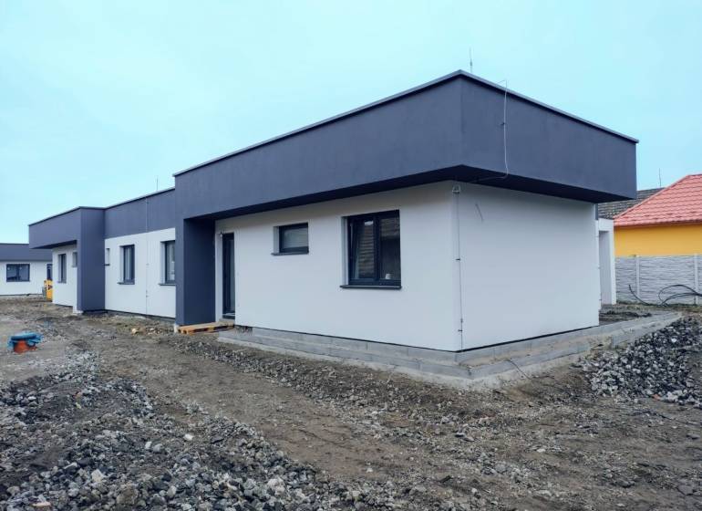 A family house in Žihárec with a white facade and a dark roof on a non-grassed plot.