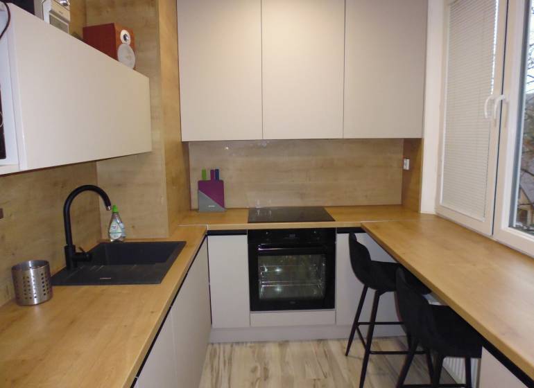 A kitchen with a wood-patterned floor in a two-room apartment, equipped with comfortable seating.