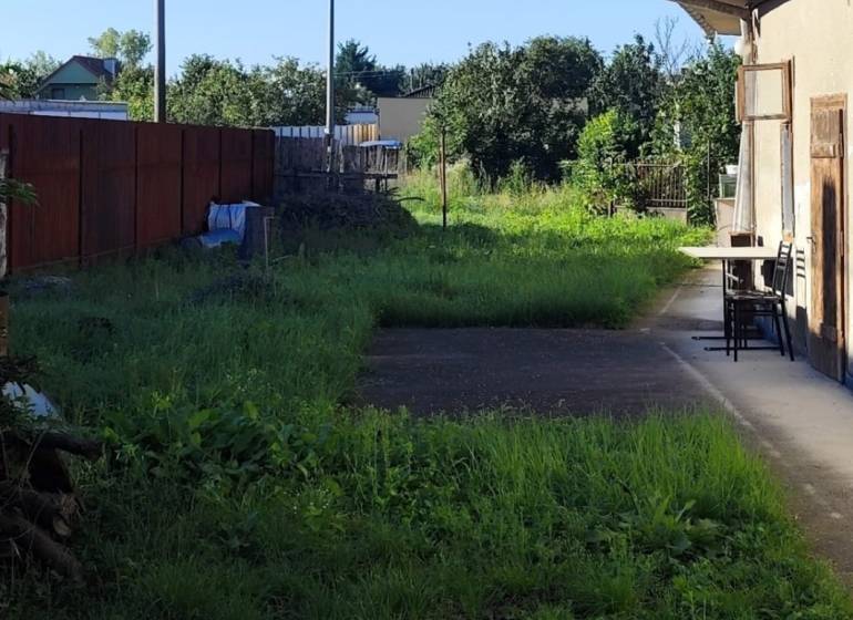A courtyard in Reca suitable for living, the plots are bordered by a fence and green shrubs.