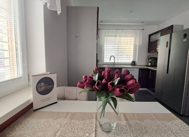 A kitchen in a family house with a vase of tulips on the table and white curtains.