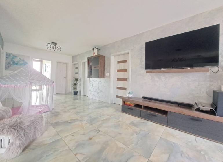 Living room in a family house with a TV on the wall, a tent, and ceramic flooring.