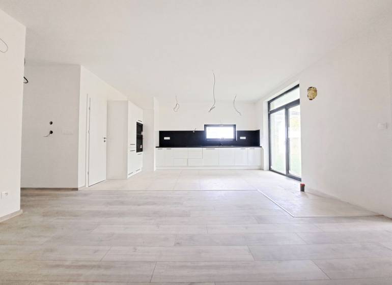 Spacious kitchen with black tiles and a wooden decor floor in a family house.