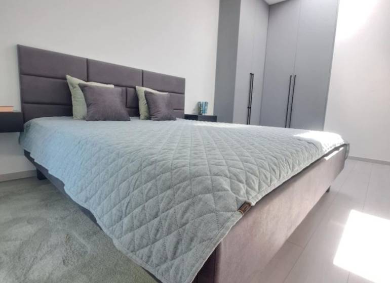 Bedroom in a 2-room apartment with light from a skylight and minimalist furnishings.