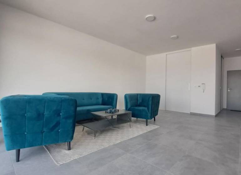 Commercial space with blue sofas, a coffee table on a carpet, and gray tiles.