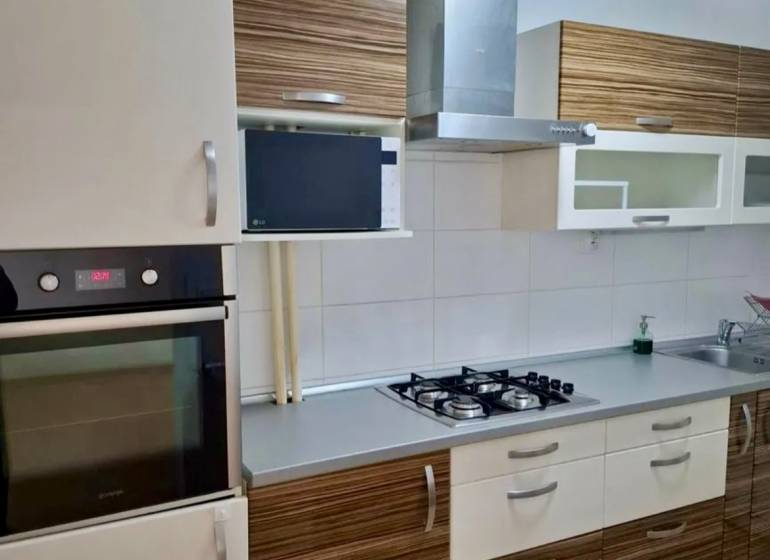 A kitchen with a stone sink, a cooktop, and an extractor hood in a 4-room apartment.