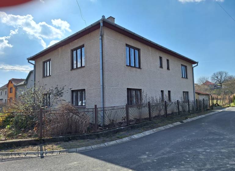 A family house in Tachtoch with plaster, next to the road and a metal fence.