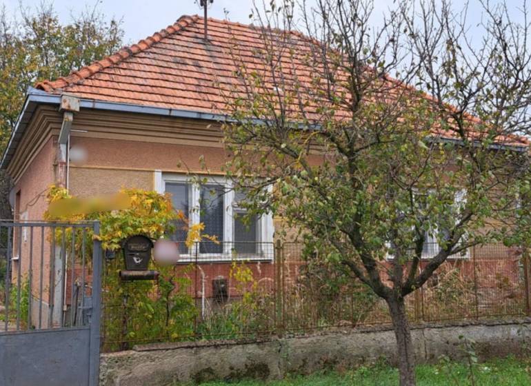 A family house in Strekov with a brick roof, a front garden, and a metal gate.
