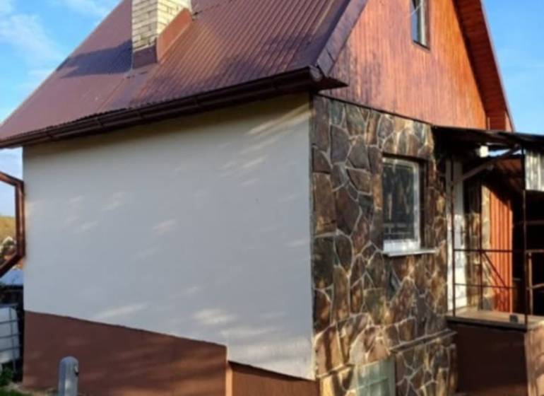 A cottage in Pozdišovce with a stone facade and a brown metal roof.