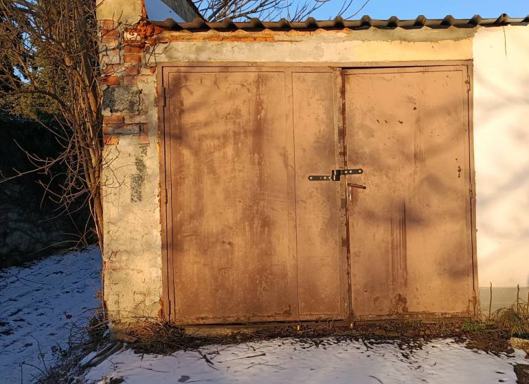 Garages on Fabrická Street in Nitra with simple doors, snowy surroundings.