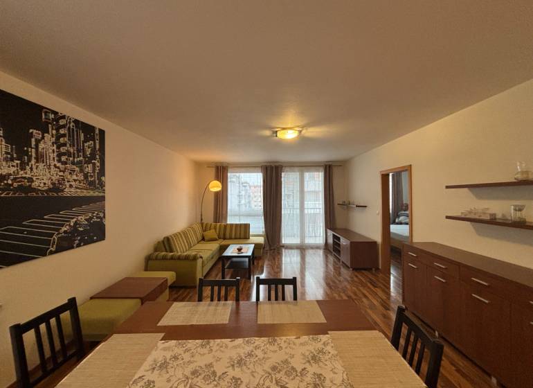 Living room with wood-patterned flooring, a sofa, and a dining table in a 2-room apartment.