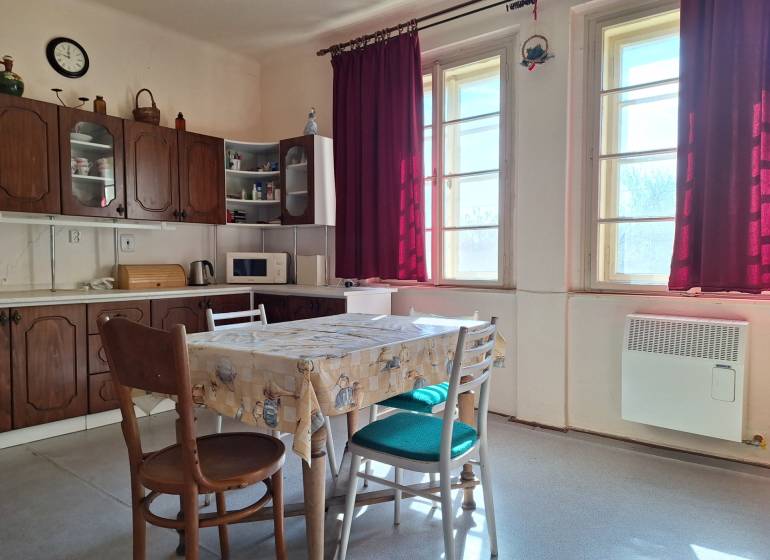 A kitchen in a family house with wooden furniture and burgundy curtains.