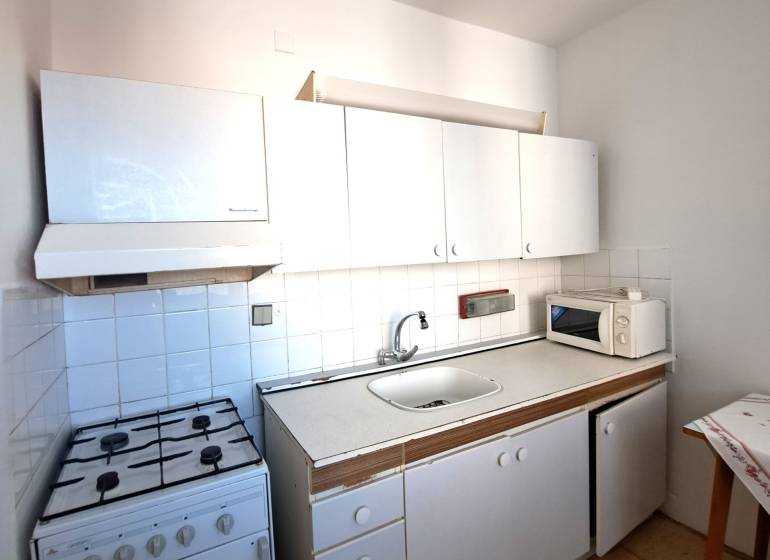A kitchen in a 4-room apartment with a stove, white cabinets, and a microwave.