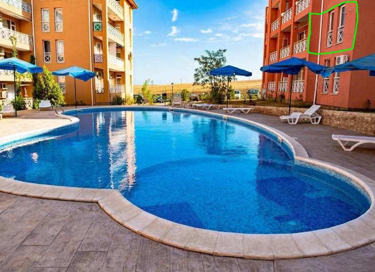 A holiday apartment in Burgas with a swimming pool, sun loungers, and umbrellas on a paved terrace.