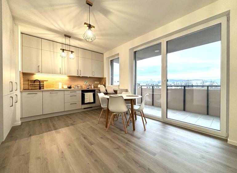 Kitchen in a 3-room apartment with a dining table, wood-patterned floor, balcony doors.