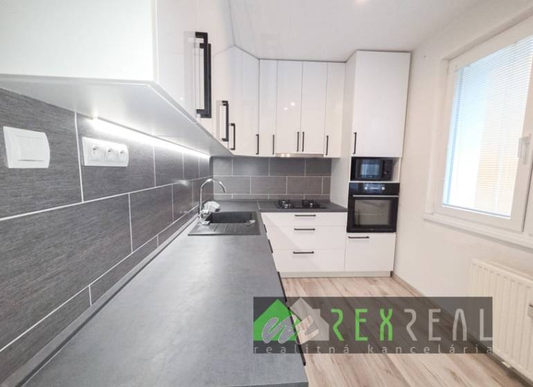 A kitchen in a 3-room apartment with white cabinets, a gray countertop, and a floor with a wooden decor.