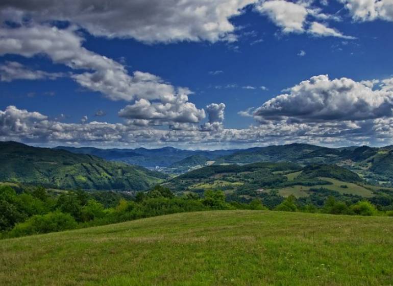 Hills and meadows around Žarnovica under the blue sky, agricultural and forest lands.