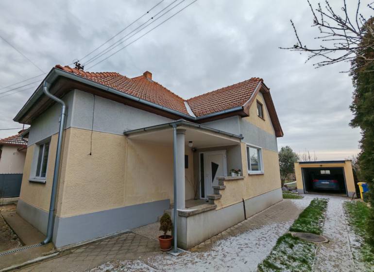 A family house in Trnovec nad Váhom with a landscaped garden and a garage on a quiet street.