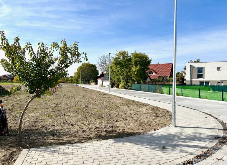 Land in Malinovo on Malinovo Street with a sidewalk, trees, and nearby houses. Plots - residential.