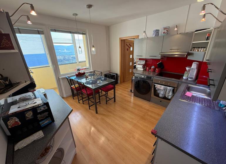 A kitchen in a 3-room apartment with a wooden decor floor and red accents.